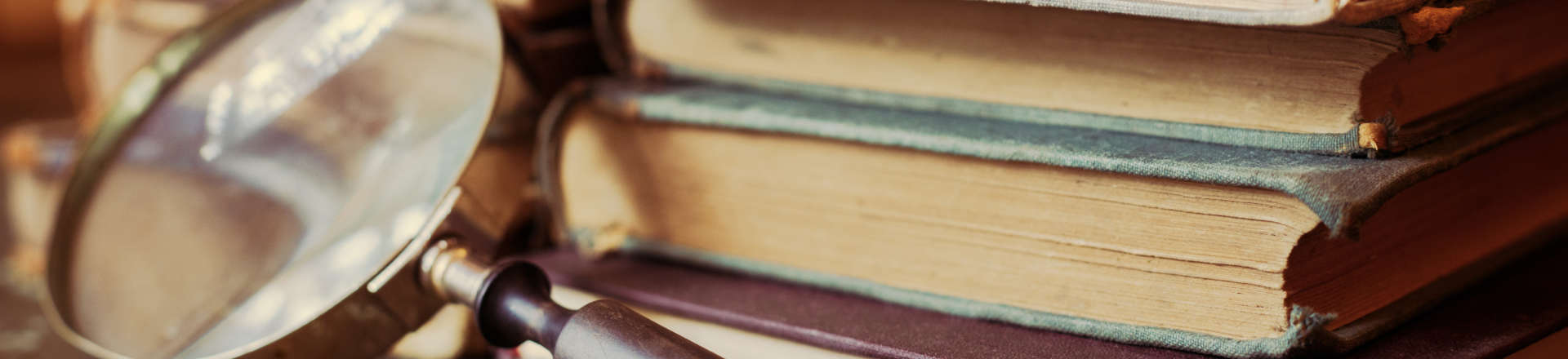 a pile of old books and a magnifying glass