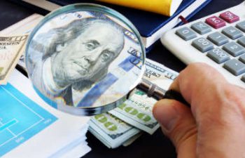 a person using a magnifying to check a banknote