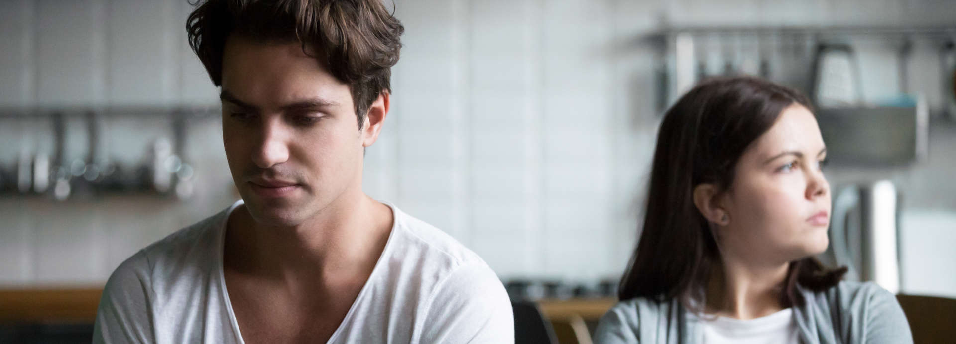 Young couple sitting in silence on a coach after having a row over infidelity