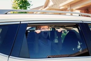 Little girl screaming, trying to get out of closed vehicle at summer.