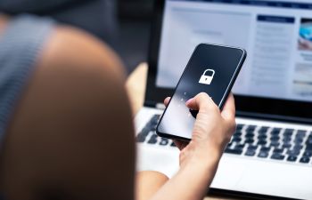 A person in front of a computer unlocking a phone to make a phone call.