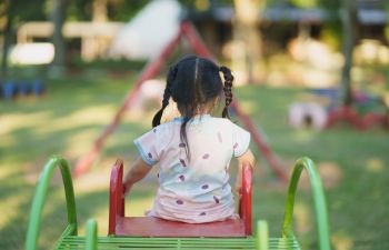 Little girl playing on a slide on a playground.