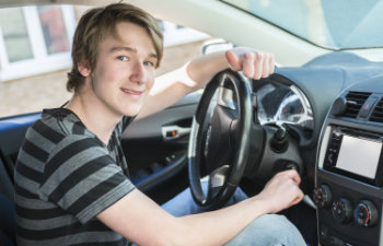 a teenage boy and new driver behind wheel of his car